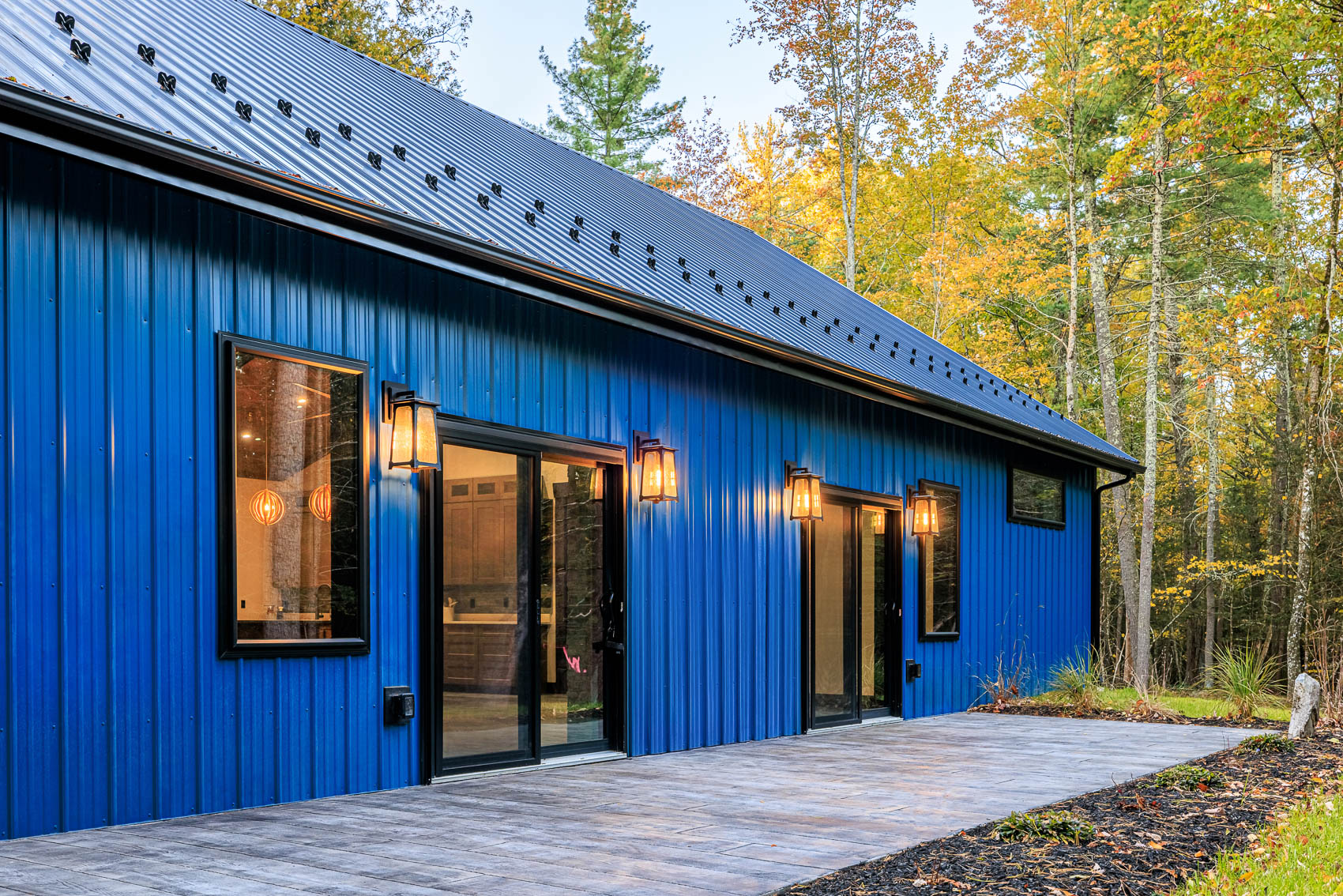 Blue barndominium side elevation with doors and exterior lighting