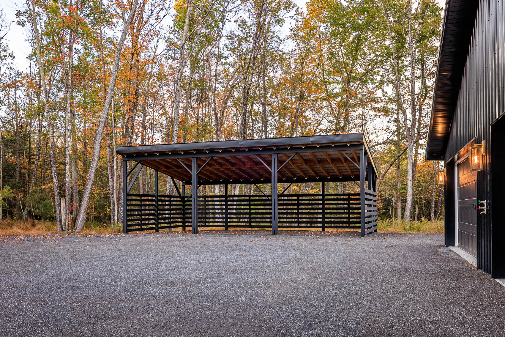 Covered parking structure beside black barndominium garage