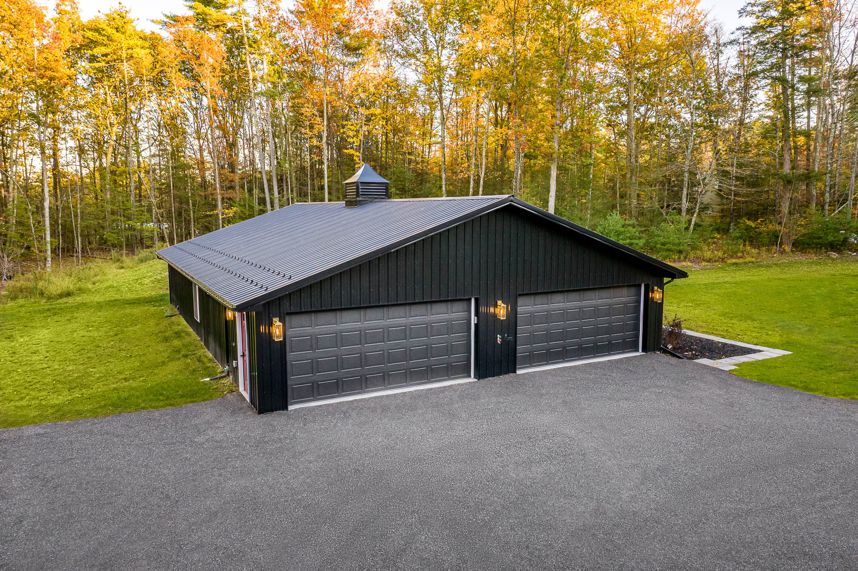 Aerial front view of black barndominium garage with two bay doors