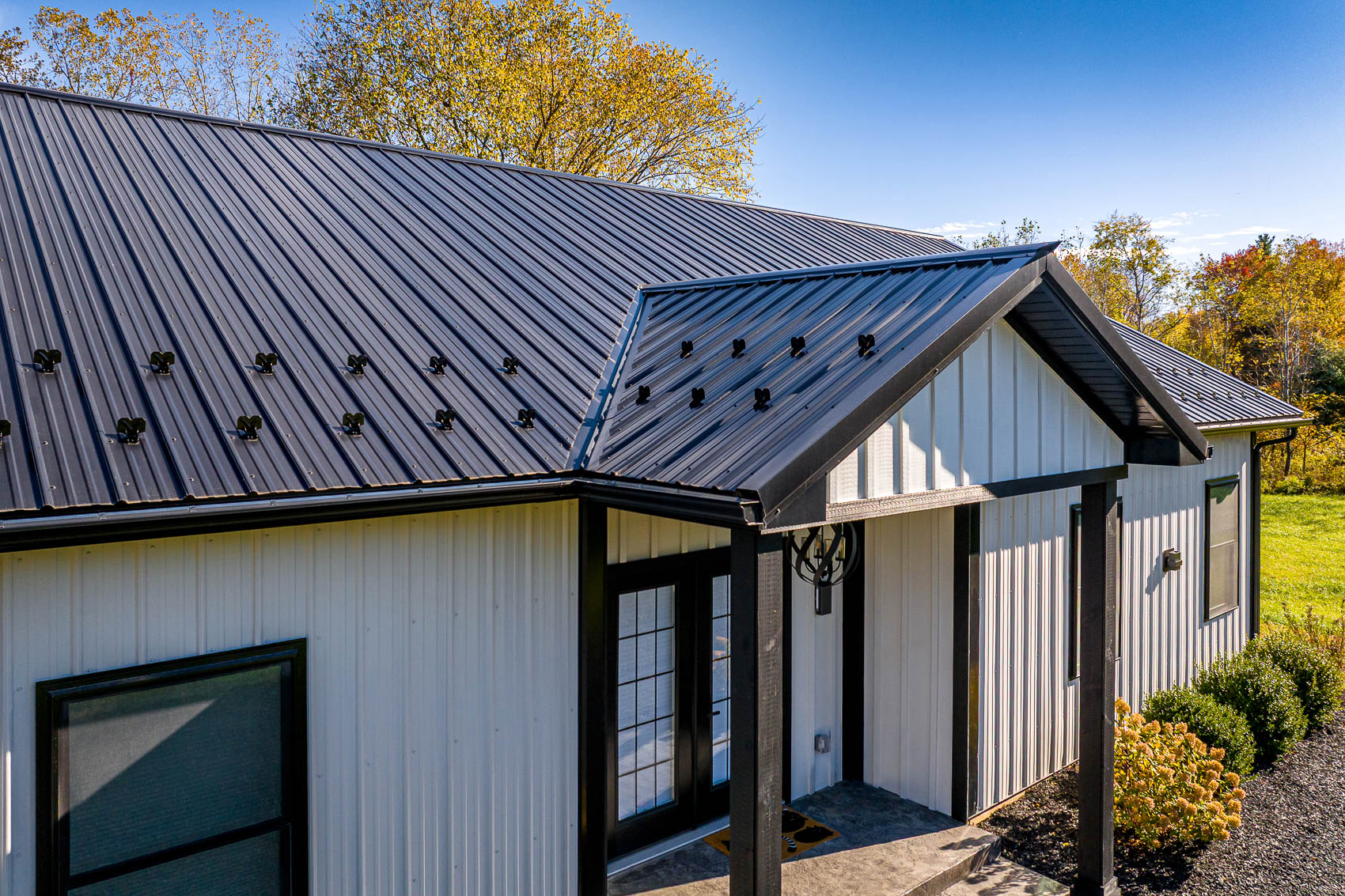 Angled roof and entry detail of white barndominium