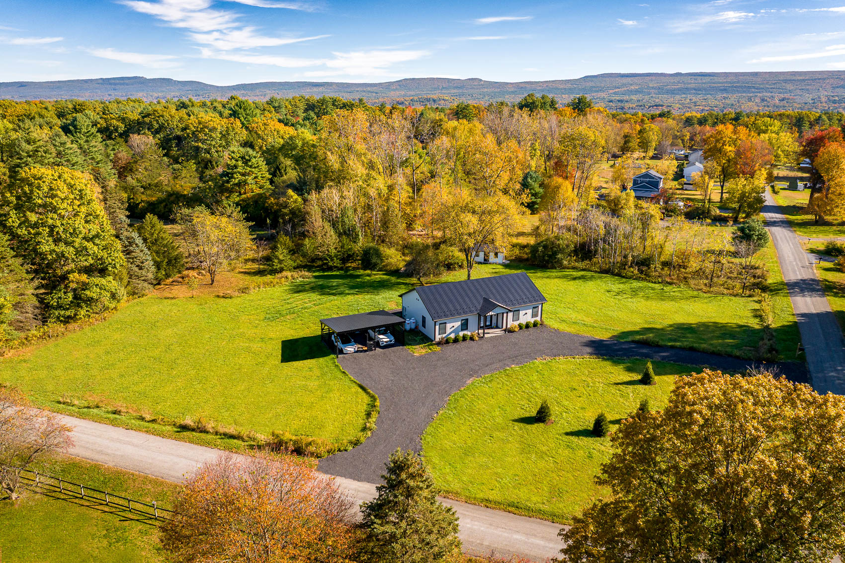Wide aerial view of white barndominium on open acreage